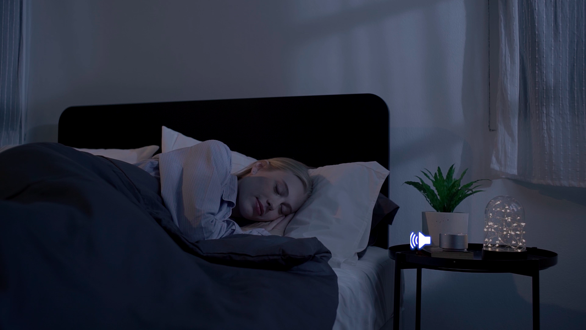 Woman resting peacefully with Banala Lite on bedside table, enhancing deep sleep through isochronic sound.